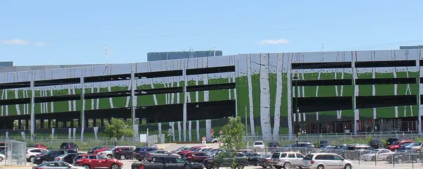 Le côté nord du complexe du Club Regent Casino à Winnipeg : son garage de stationnement à plusieurs niveaux habillé d'une murale de bouleaux, au-dessus d'un stationnement plein
